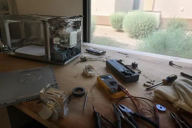 Disassembled microwave on a workbench with repair tools in a workshop in Gilbert, AZ.