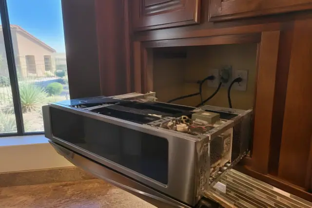 Technician repairing a microwave removed from a cabinet in a Peoria, AZ home.