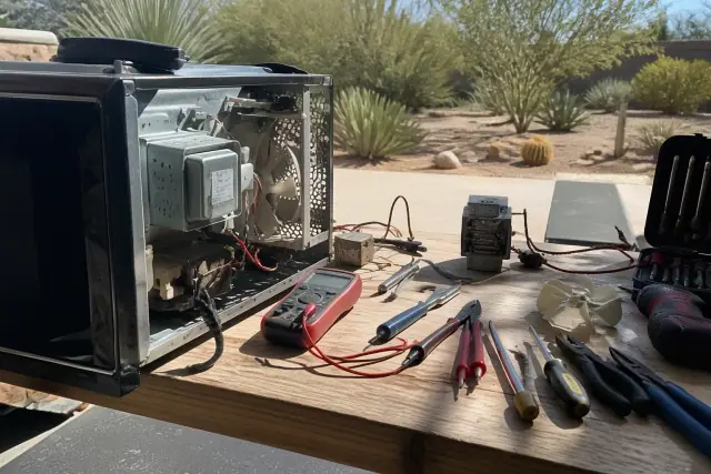 Disassembled microwave parts and tools on a workbench during a repair in Paradise Valley, AZ.
