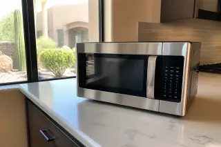 Stainless steel microwave on a kitchen island with a clean control panel and trim kit in a Phoenix, AZ home.