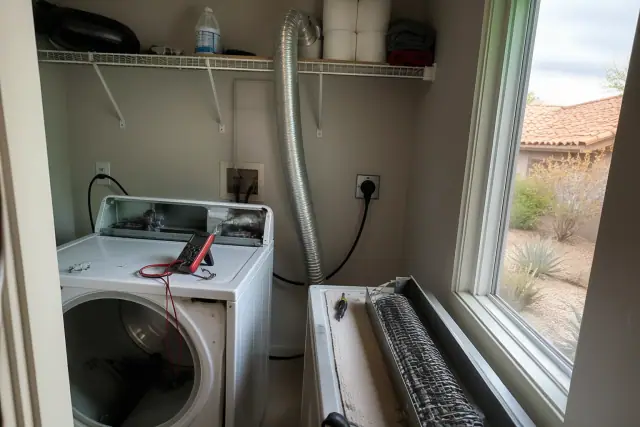 A dryer with a disconnected heating element and multimeter during a repair in a laundry closet in Phoenix, AZ.
