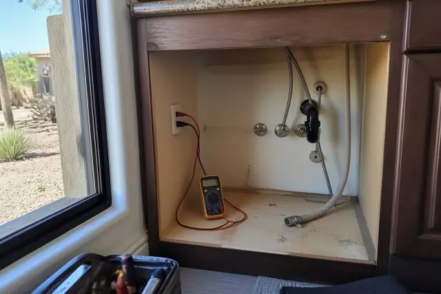 Multimeter testing electrical wiring for a garbage disposal installation in a kitchen in Phoenix, AZ.