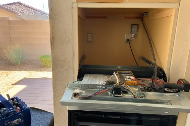 Technician repairing a built-in oven with exposed wiring at a jobsite in Avondale, AZ.