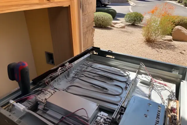 Technician repairing a built-in oven with exposed wiring in a Mesa, AZ kitchen.