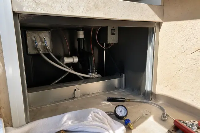 Contractor performing preventive ice maker maintenance with tools in an under-counter space in Phoenix, AZ.