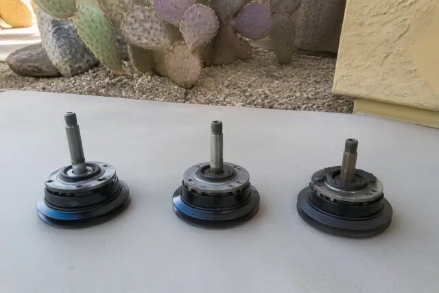 Three worn mechanical parts lined up on a concrete floor near a desert landscape in Phoenix, AZ.