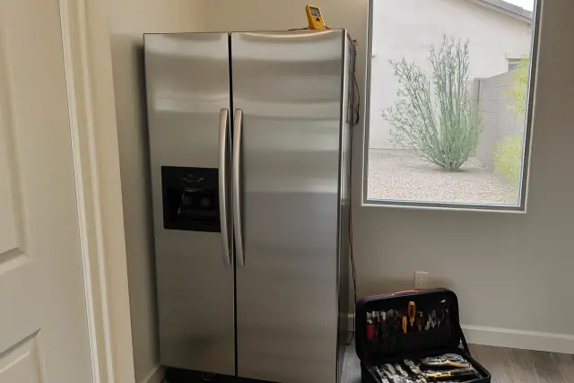 Side-by-side refrigerators undergoing repair in a Phoenix, AZ pantry with a technician's toolkit and multimeter.