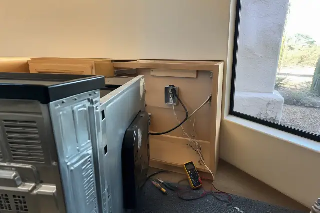 Technician repairing a stove in a Paradise Valley, AZ kitchen with electrical tools and wiring visible.