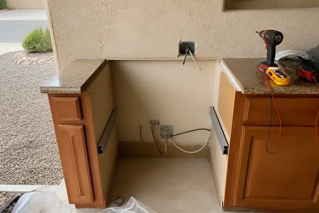 Technician performing stove and range electrical repairs on a kitchen cabinet cutout in Avondale, AZ.