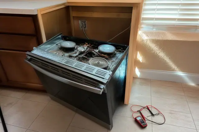 A technician inspects a stove pulled from a cabinet for repairs in a Phoenix, AZ home.