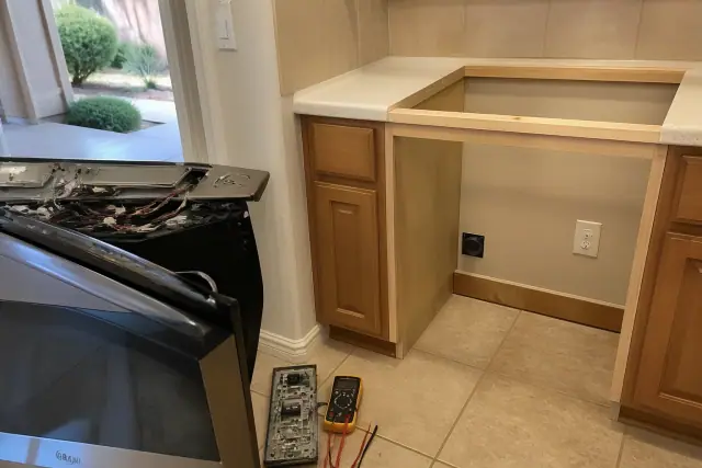 A technician repairing a kitchen stove with a multimeter in a home in Gilbert, AZ.