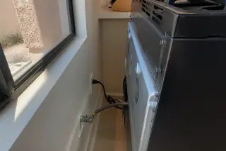 Gas line and power cord connections behind a freestanding stove in a Phoenix, AZ kitchen.