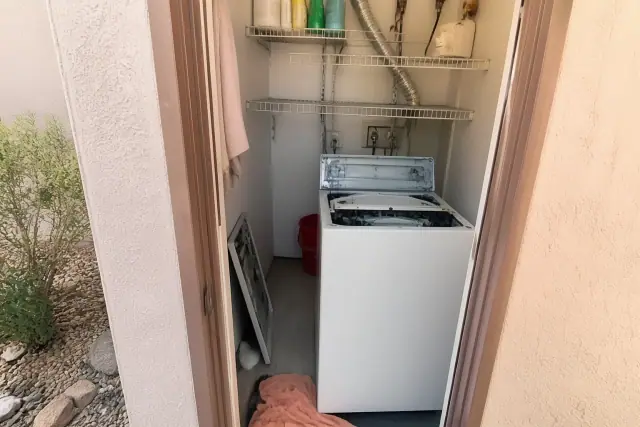 Technician repairing a washing machine in a laundry closet in Scottsdale, AZ.