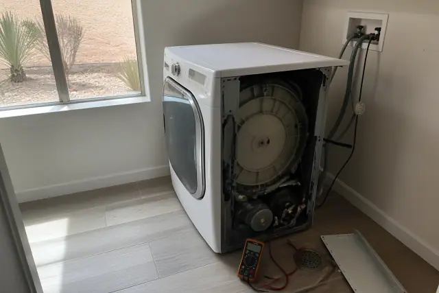 Technician repairing a washing machine in a laundry alcove in Mesa, AZ.