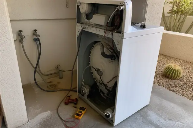 Technician performing washer repair in a utility alcove at a home in Tempe, AZ.