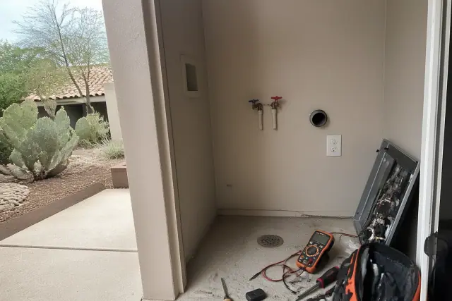 Technician using a multimeter to repair a washing machine in a Paradise Valley, AZ utility alcove.