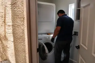 Technician performing a final inspection of a washing machine in a laundry room in Phoenix, AZ.
