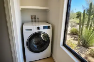 Functional washing machine installed in a laundry closet with desert view through a window in Phoenix, AZ.