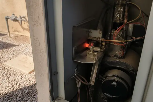 A glowing, weak gas dryer igniter during a delayed start in a Phoenix, AZ utility cabinet.
