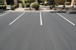 Textured asphalt surface after a milling job in a Phoenix, AZ retail parking lot with desert landscaping.