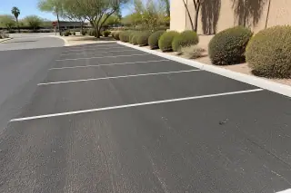 Freshly milled and swept dark asphalt parking spaces with desert xeriscaping in Phoenix, AZ.