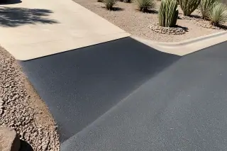 Newly paved asphalt driveway transition with desert gravel and cacti in Phoenix, AZ.