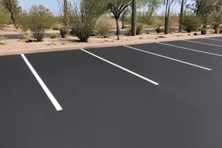 Fresh black asphalt parking stalls with white lines and desert ocotillo and saguaro cacti in Phoenix, AZ.