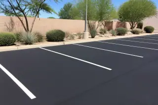 Newly sealcoated parking stalls with clean edges and desert landscaping in Phoenix, AZ.