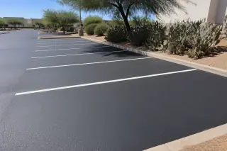 Freshly sealcoated parking stalls with white lines and prickly pear cacti in Phoenix, AZ.