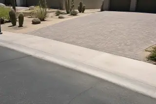 Newly paved driveway apron transitioning to the street with desert landscaping in Phoenix, AZ.