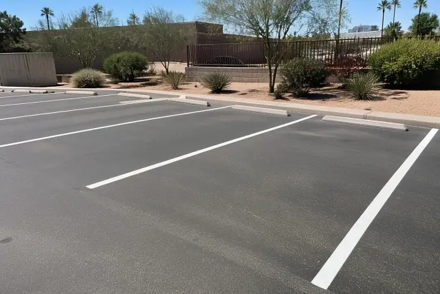 Freshly painted white parking stall lines on asphalt in a retail parking lot in Phoenix, AZ.
