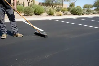 Contractor sweeping debris near freshly paved parking stalls in Phoenix, AZ.