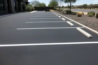 Newly painted parking space lines on fresh asphalt with volcanic rock landscaping in Phoenix, AZ.