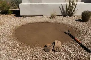 Circular soil depression from a removed cactus in a gravel yard in Phoenix, AZ.