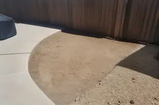 Sun-bleached decomposed granite and cleared earth near a patio and fence in Phoenix, AZ.
