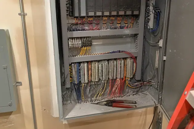 Technician wiring a building automation control cabinet with color-coded wires at a commercial jobsite in Scottsdale, AZ.