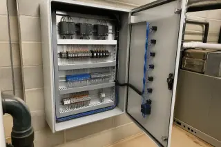 Building automation control cabinet with organized wiring and terminal blocks on a masonry wall in Phoenix, AZ.