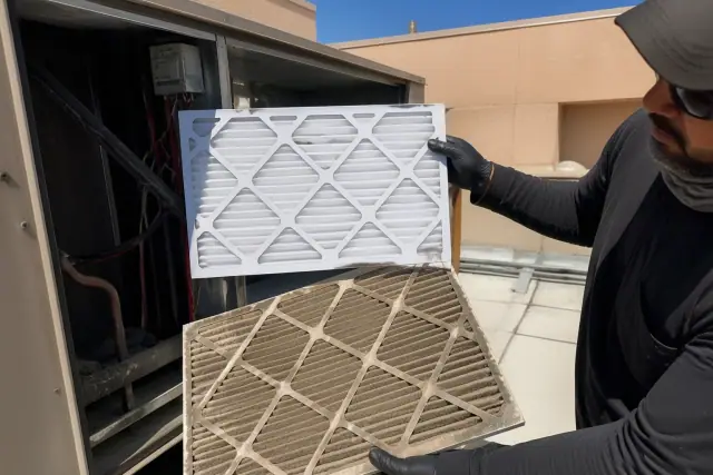 Technician comparing a dirty HVAC filter to a clean one during a rooftop unit maintenance service in Phoenix, AZ.