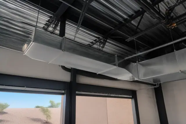 Galvanized steel ductwork hanging from the ceiling of an industrial warehouse in Goodyear, AZ.
