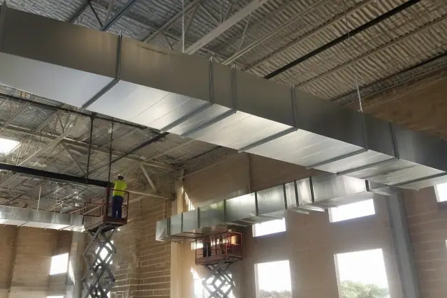 Galvanized steel rectangular ductwork suspended from the ceiling at a commercial construction site in Glendale, AZ.