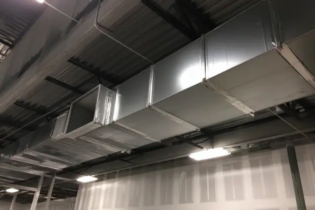 Galvanized steel rectangular ductwork suspended from an industrial ceiling in a Gilbert, AZ warehouse.