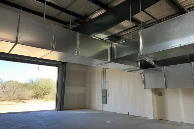 Galvanized steel ductwork installation suspended from an industrial ceiling in a Mesa, AZ warehouse.