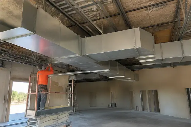 Sheet metal workers installing galvanized steel ductwork in a Chandler, AZ commercial building.