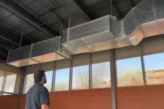 Galvanized steel ductwork suspended from an industrial ceiling with desert views in Phoenix, AZ.