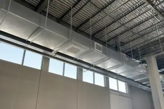 Finished galvanized steel ductwork suspended near concrete walls and clerestory windows in Phoenix, AZ.