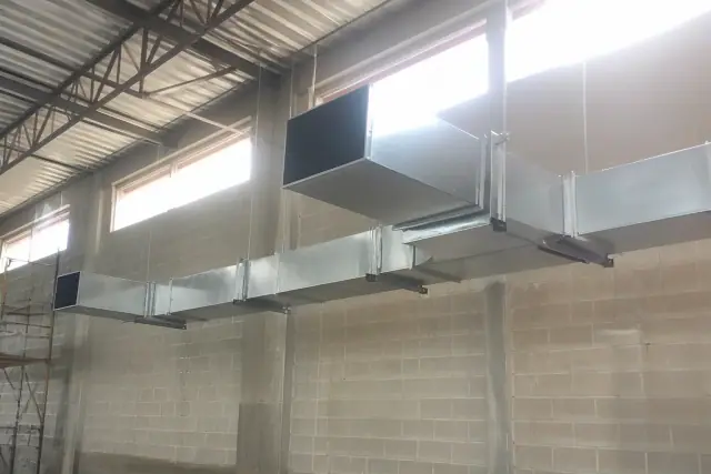 Galvanized steel ductwork installation suspended from the ceiling of a warehouse in Phoenix, AZ.