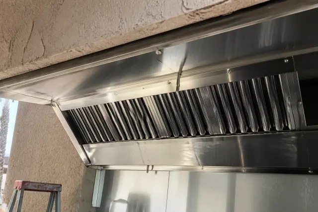 Stainless steel hood assembly with grease baffles installed at a kitchen ventilation project site in Phoenix, AZ.