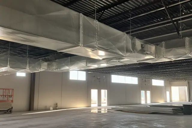 Installed galvanized steel HVAC ductwork hanging from the ceiling of a warehouse in Phoenix, AZ.