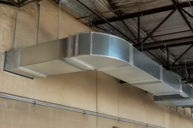 Galvanized steel ductwork installation with foil tape and rod hangers in a Mesa, AZ industrial warehouse.