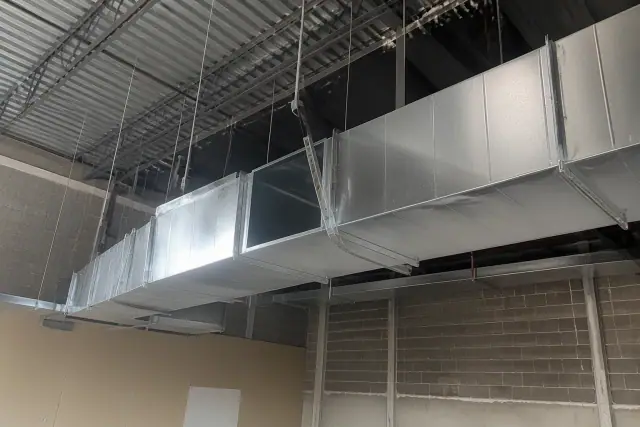 Sheet metal workers installing galvanized steel rectangular ductwork from an industrial ceiling in Gilbert, AZ.